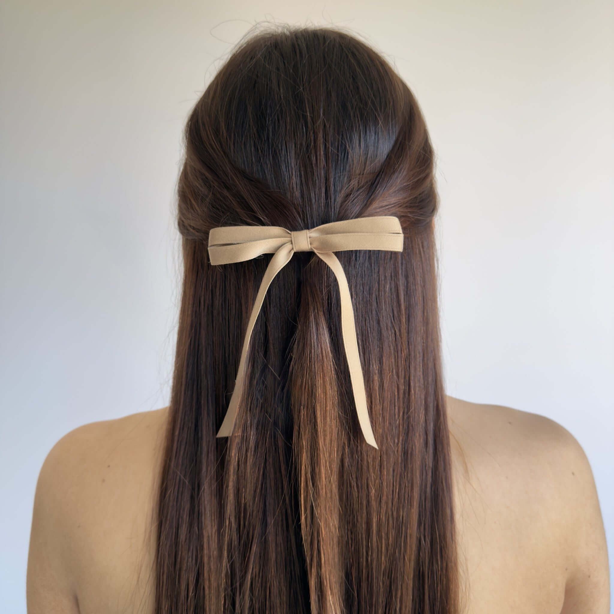 Model wearing Olivia petite matte satin hair bow in taupe.