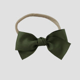 Moss green grosgrain Kayla hair bow on a nude nylon headband against a white background