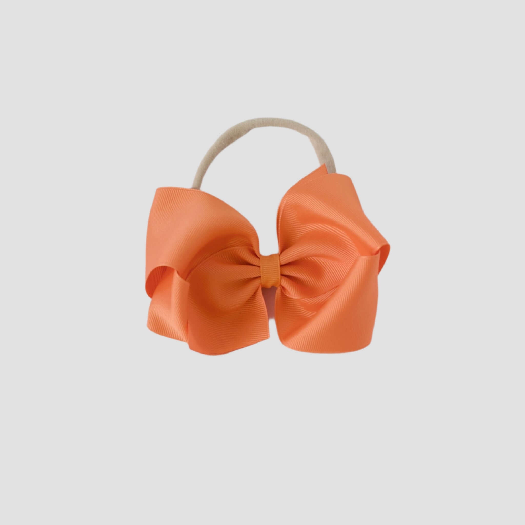 Pumpkin orange hair bow headband on a white background