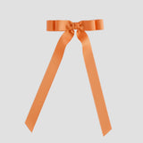 Pumpkin orange long tail ribbon bow on a white background