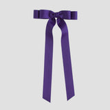 Purple bow with long ribbon tails on a white background