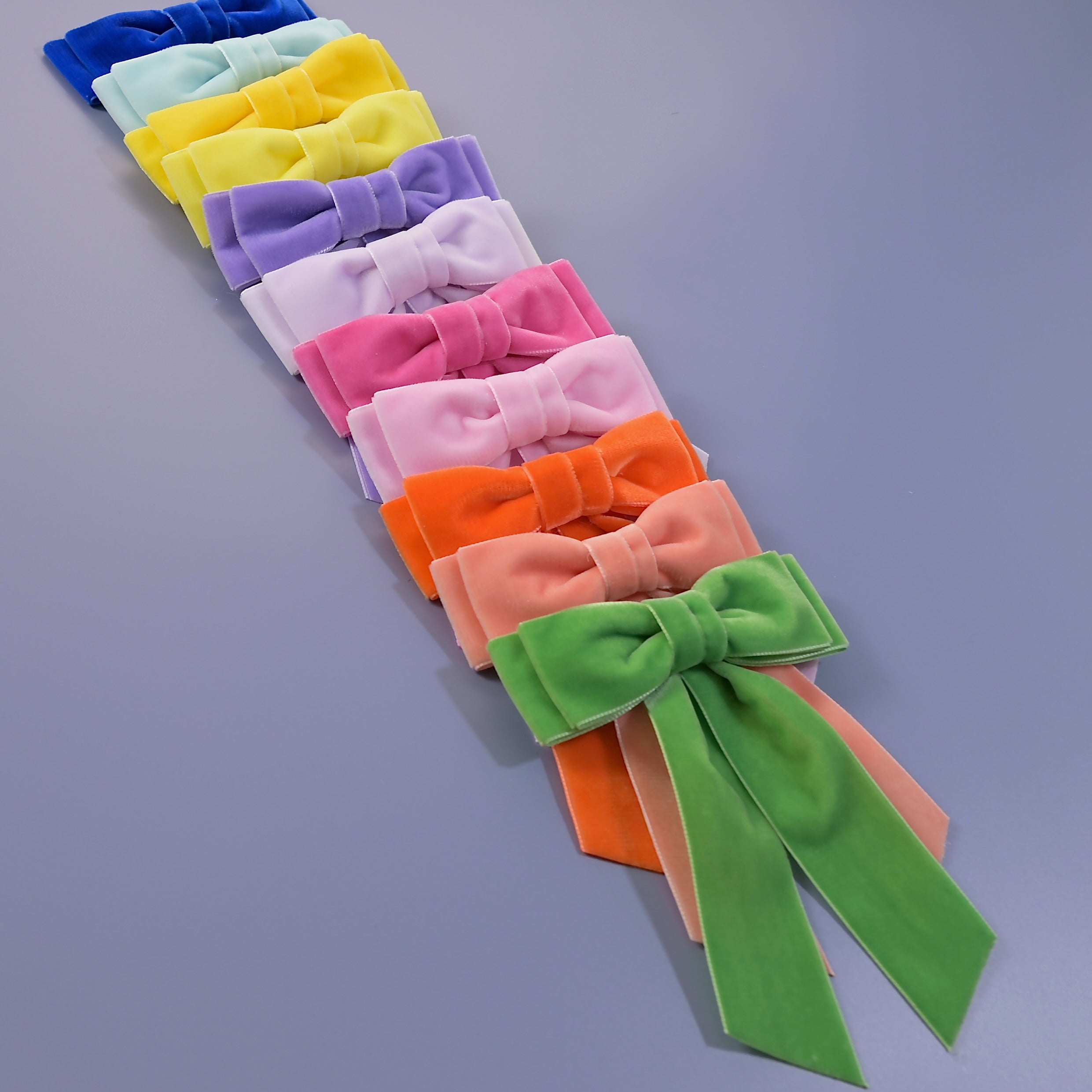Spring/Summer Velvet Mia hair bow collection on a slate blue background