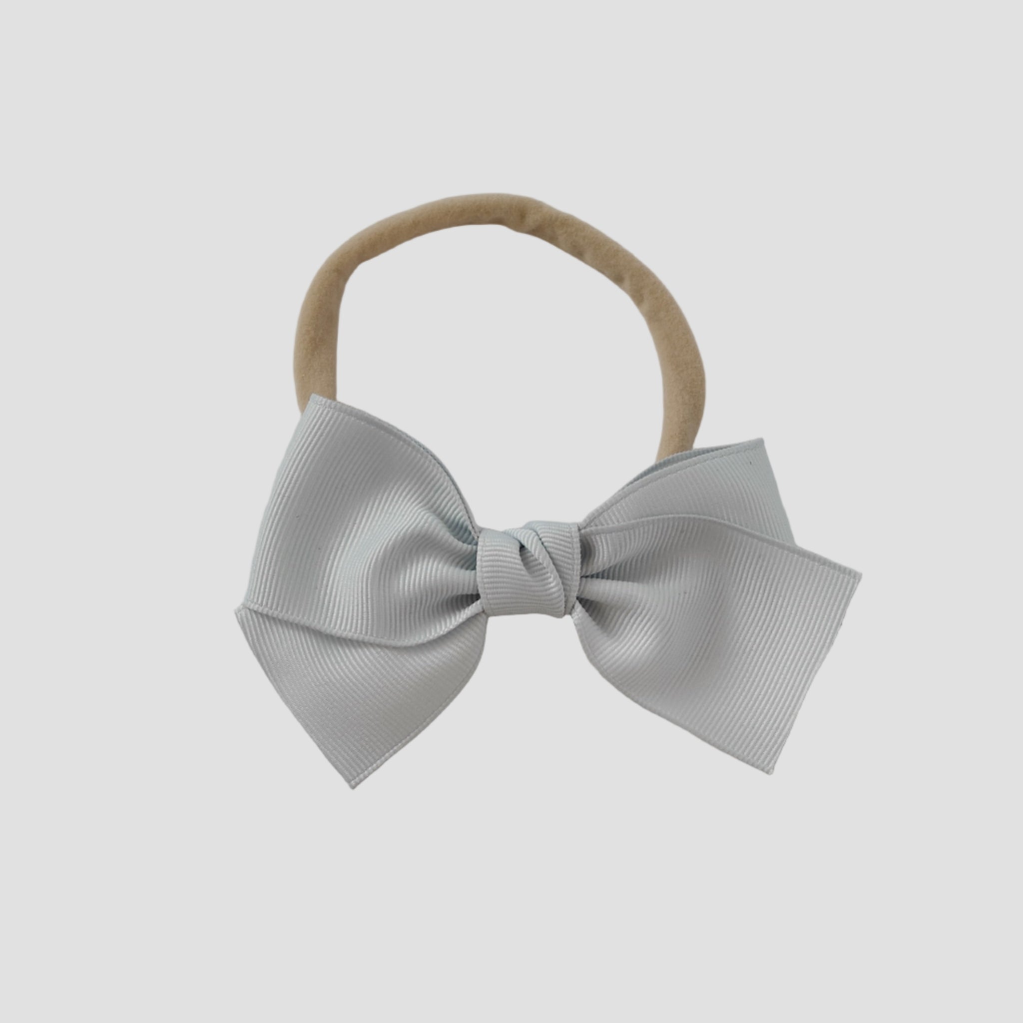 Silver grosgrain Kayla bow on a nude nylon headband against a white background
