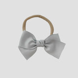 Silver grosgrain Kayla bow on a nude nylon headband against a white background