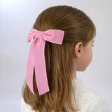 Little girl wearing a half-up hairstyle with the Zoe petite velvet bow in blush 