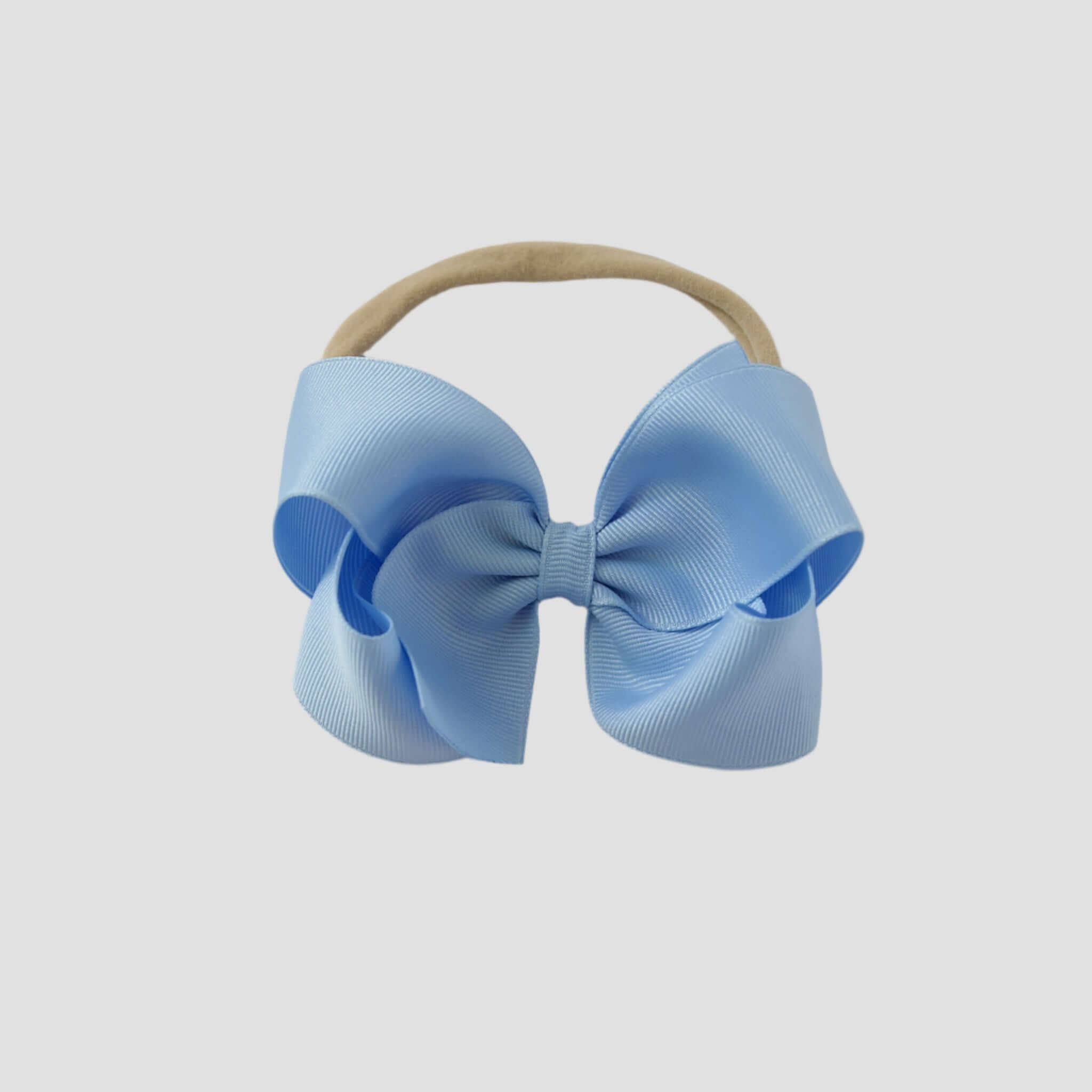 Light blue hair bow on a nude nylon headband against a white background