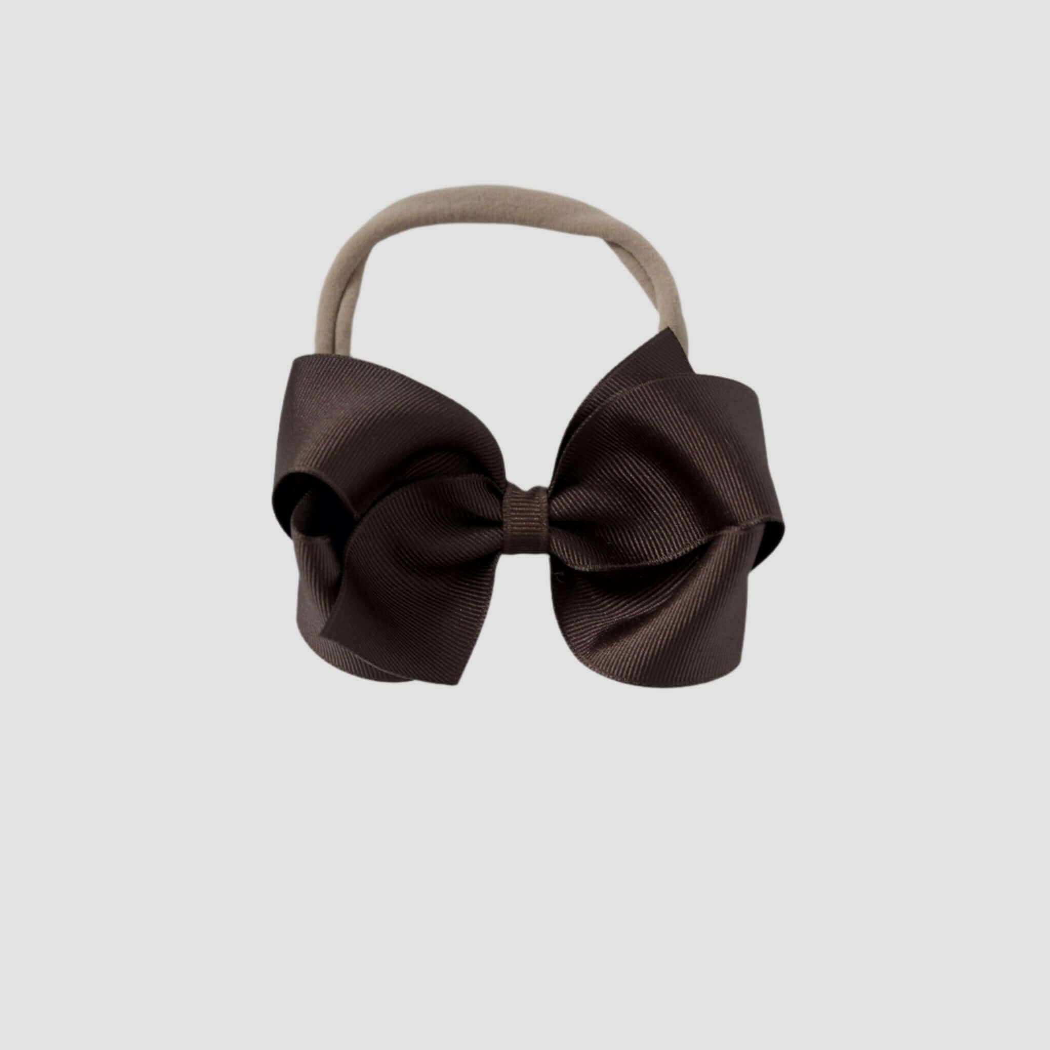 Brown hair bow on a nude nylon headband on a white background