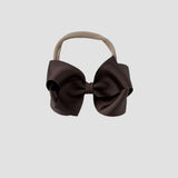 Brown hair bow on a nude nylon headband on a white background
