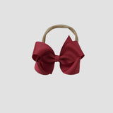 Red hair bow on a nude nylon headband on a white background