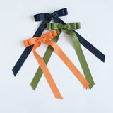 Three ribbons in navy, moss green, and pumpkin orange on a white background