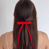 Model wearing Olivia skinny velvet bow in red.