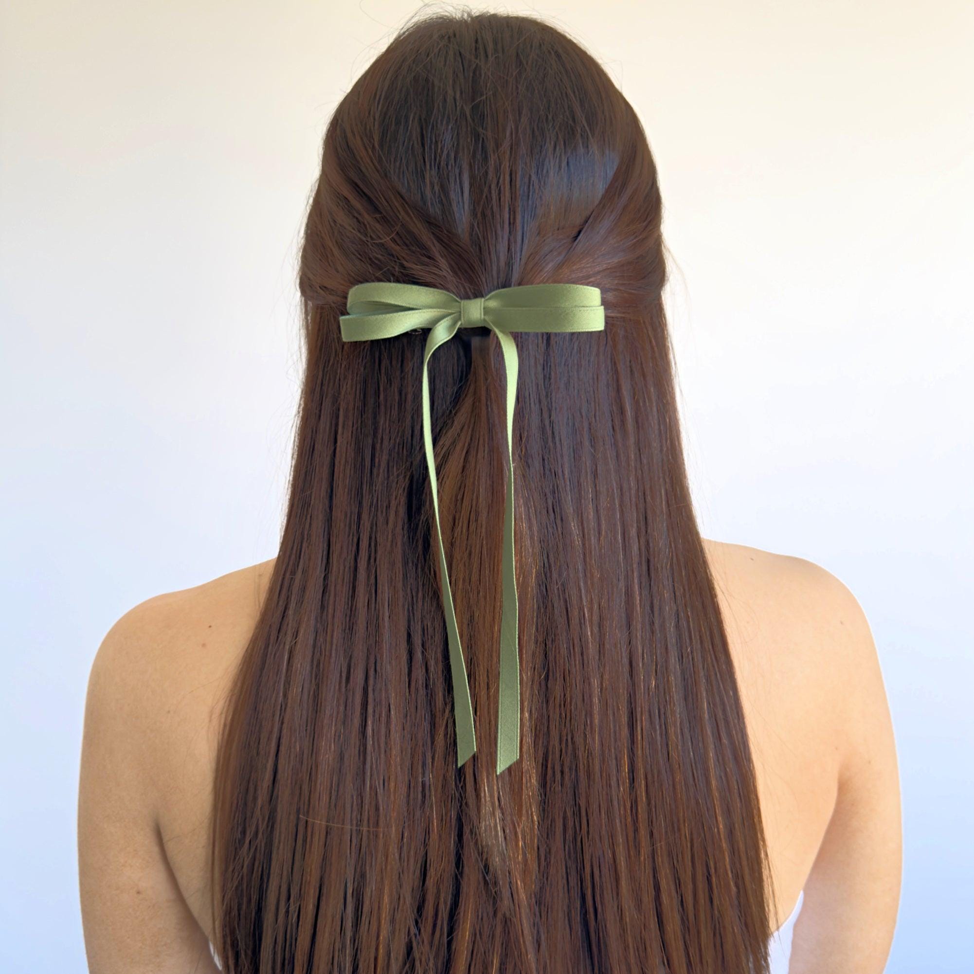 Olivia Matte Satin Bow in green, handcrafted with sustainable recycled ribbon, worn in long hair for a stylish look.