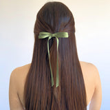 Olivia Matte Satin Bow in green, handcrafted with sustainable recycled ribbon, worn in long hair for a stylish look.