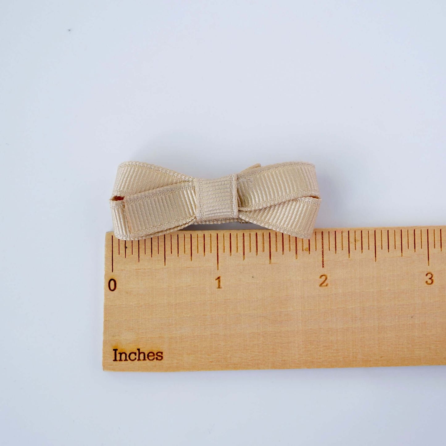 Neutral mini grosgrain bow with snap clip, shown next to a ruler for size reference, perfect hair accessory for babies and toddlers.