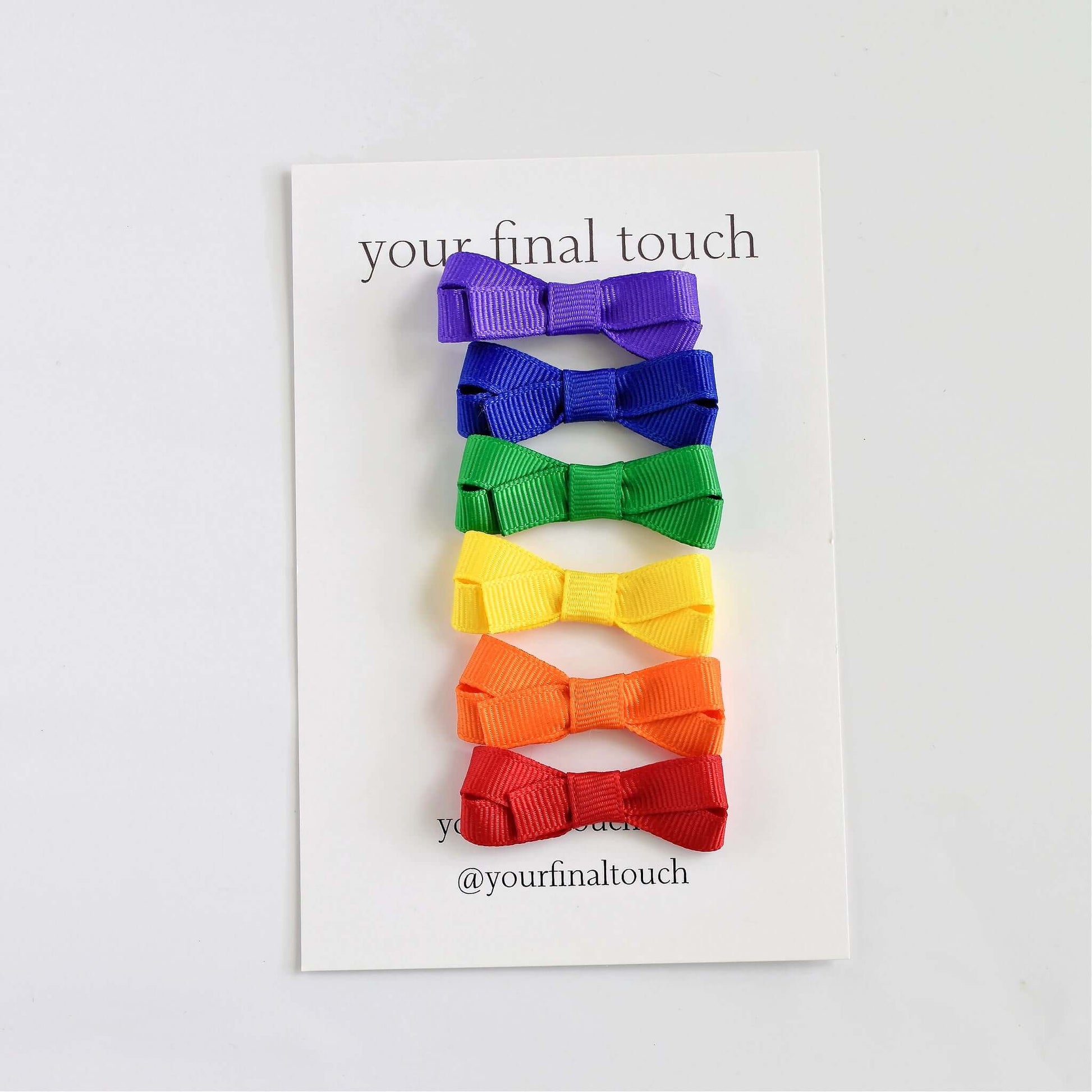 Penelope mini grosgrain hair bows in bright rainbow colors for babies and toddlers on display card