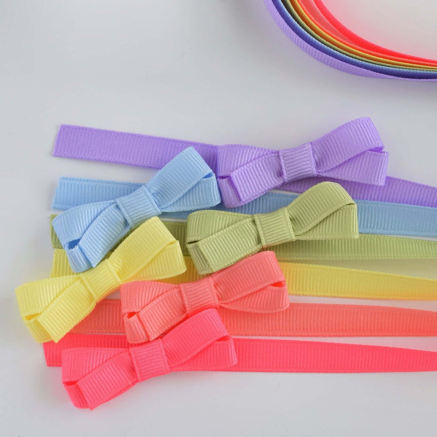 Mini grosgrain hair bows in pastel colors for baby and toddler girls, featuring no-slip snap grips. Perfect for cute hairstyles!