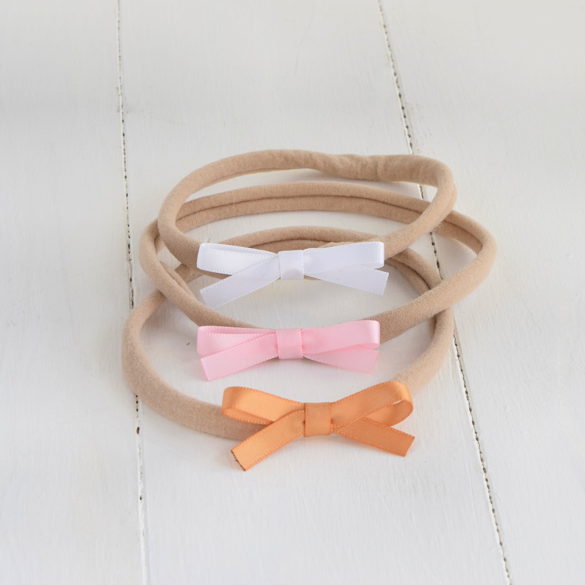 satin bow headband in white, pink and gold.