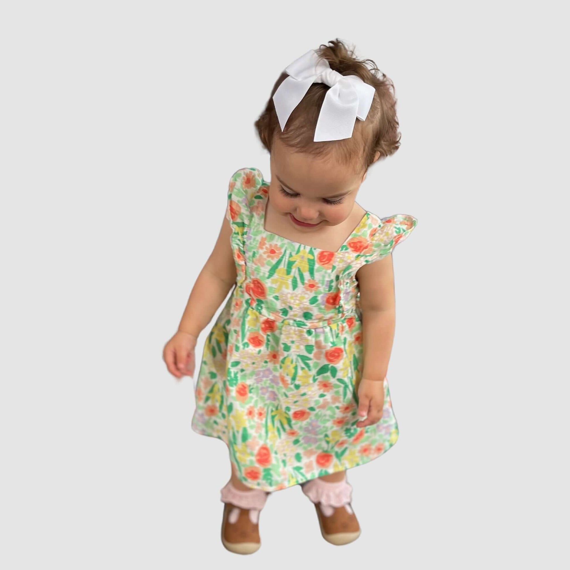 Toddler wearing a floral dress with a white grosgrain sailor bow in her hair