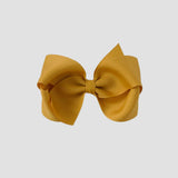 mustard yellow hair bow on a white background