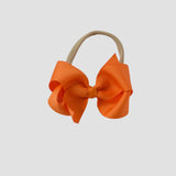 Orange hair bow a nude nylon headband on a white background