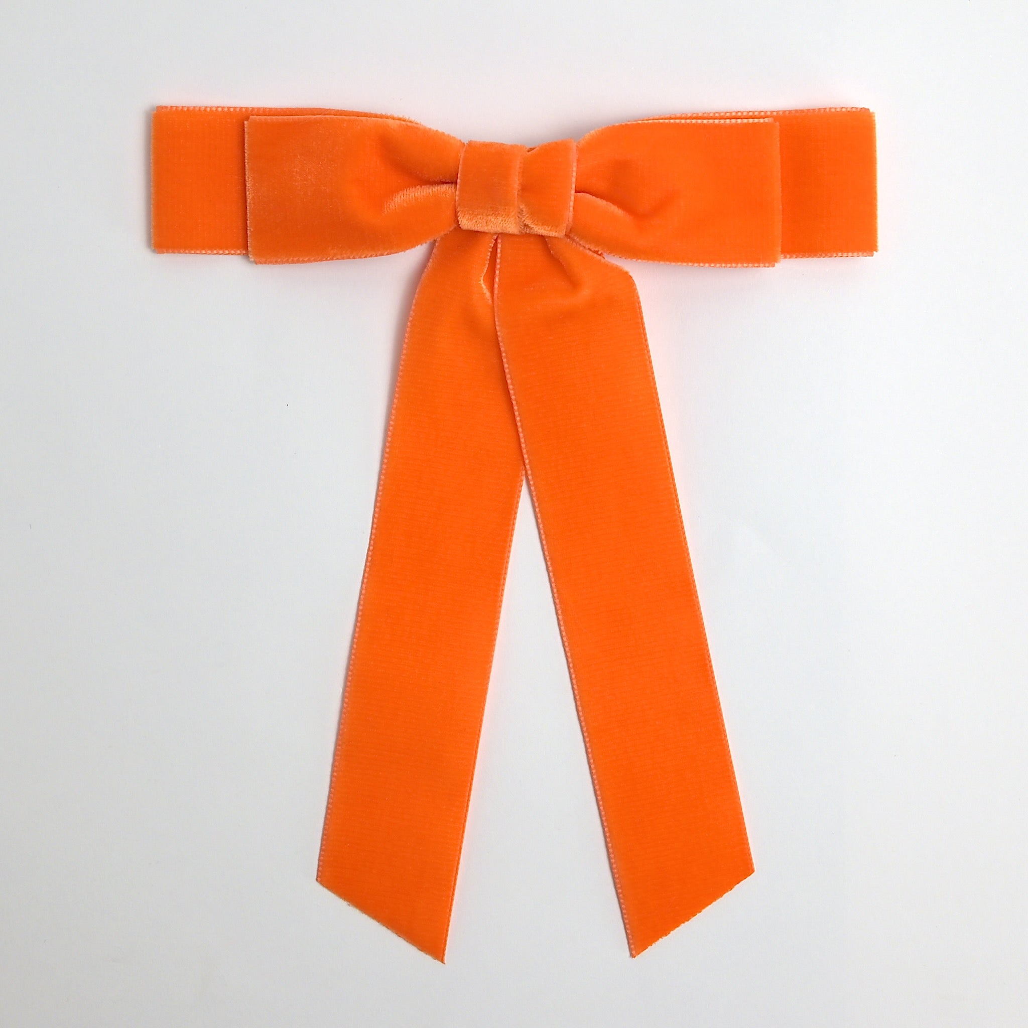 Orange Grace velvet hair bow for women. Double bow with long tails on white background 