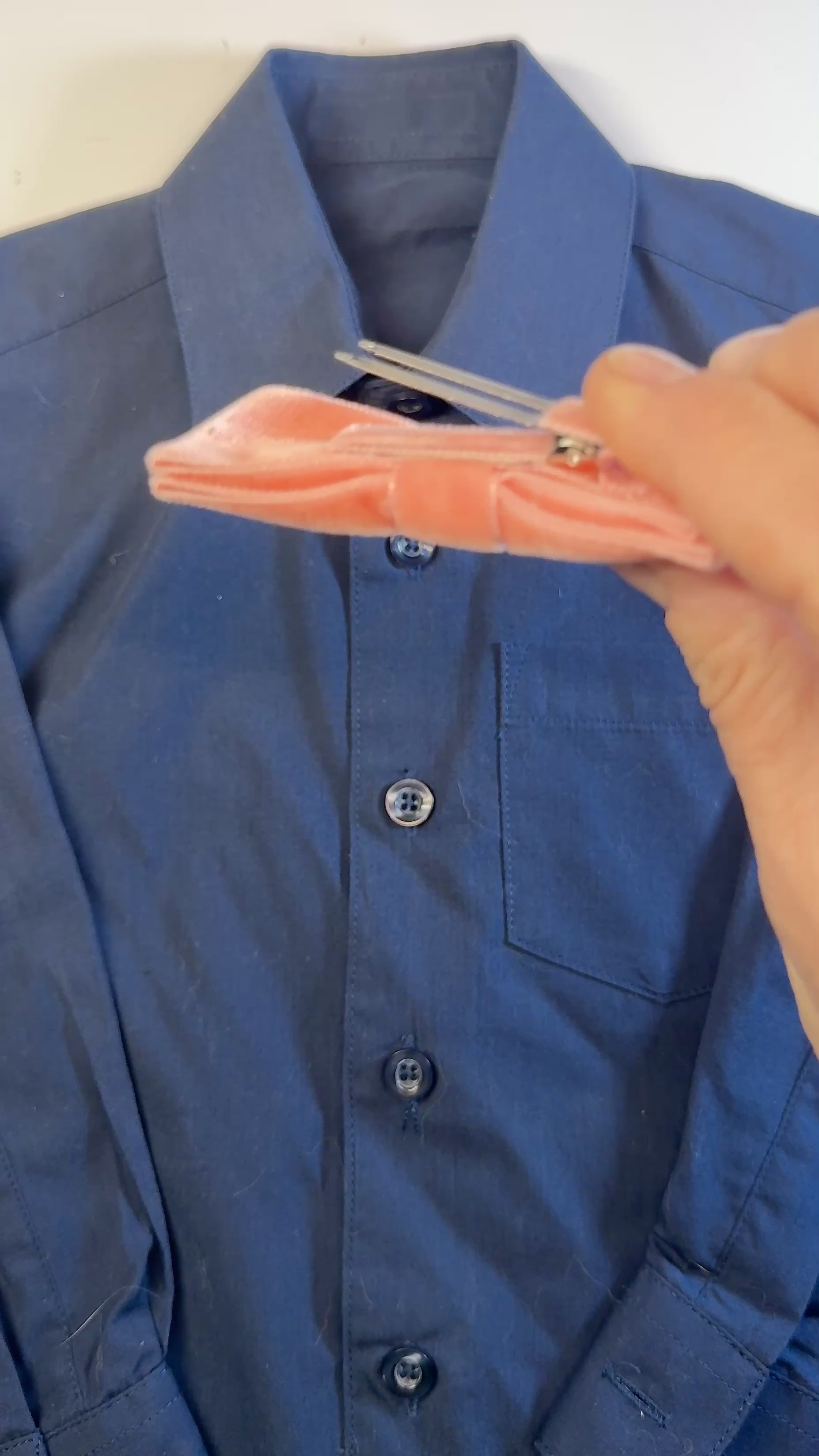 Video showing how to slip clip bow tie over top shirt button.