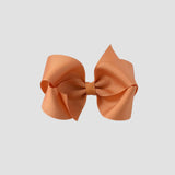 Pumpkin orange hair bow on a white background