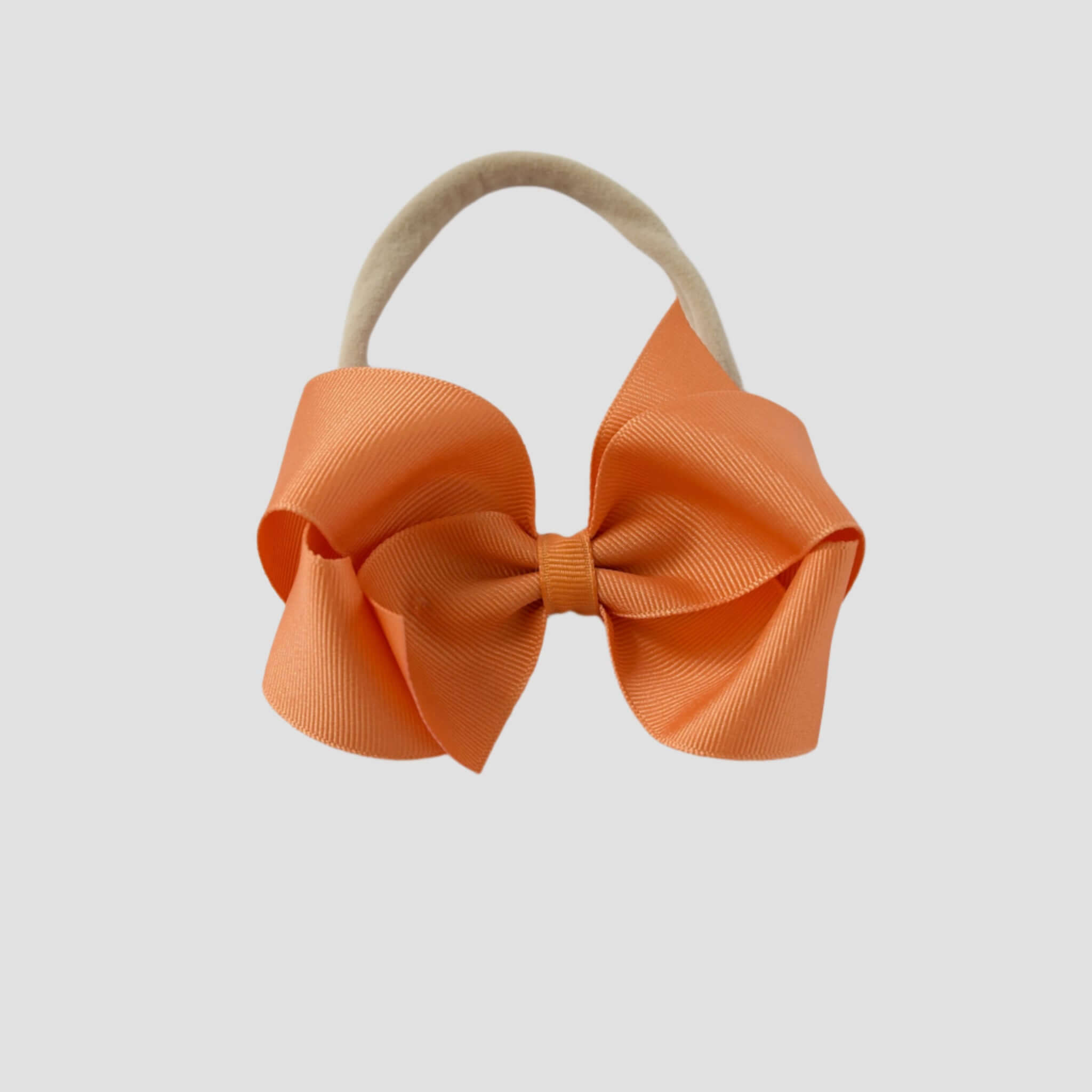 Pumpkin orange bow on a nude nylon headband.