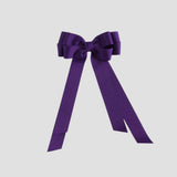 Purple bow with long tails on a white background