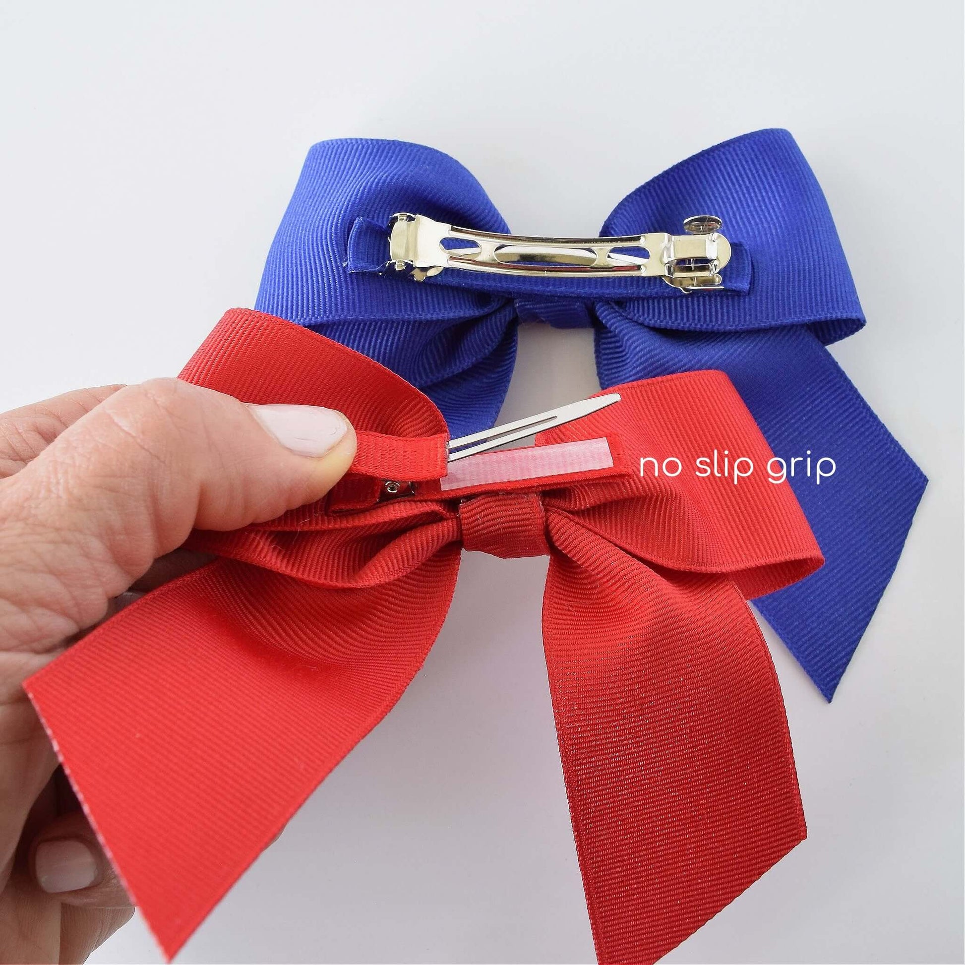 Close-up of handmade grosgrain Sailor hair bows in red and blue, showcasing no-slip grip alligator clips and French barrette.
