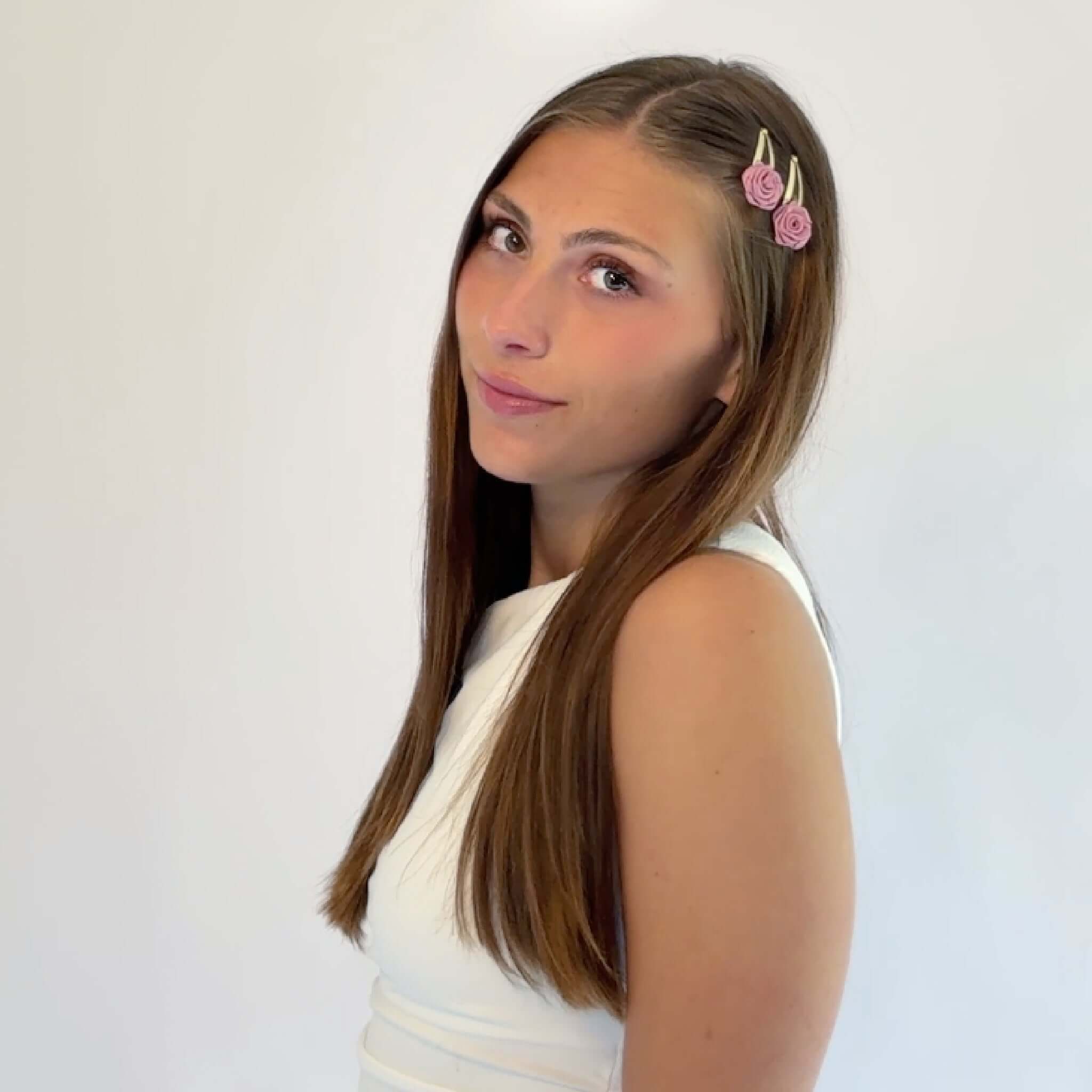 Woman wearing two pink satin rosette snap clips on side-parted hair