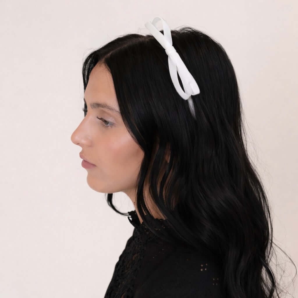 young women with dark hair wearing the Olivia velvet bow headband in white