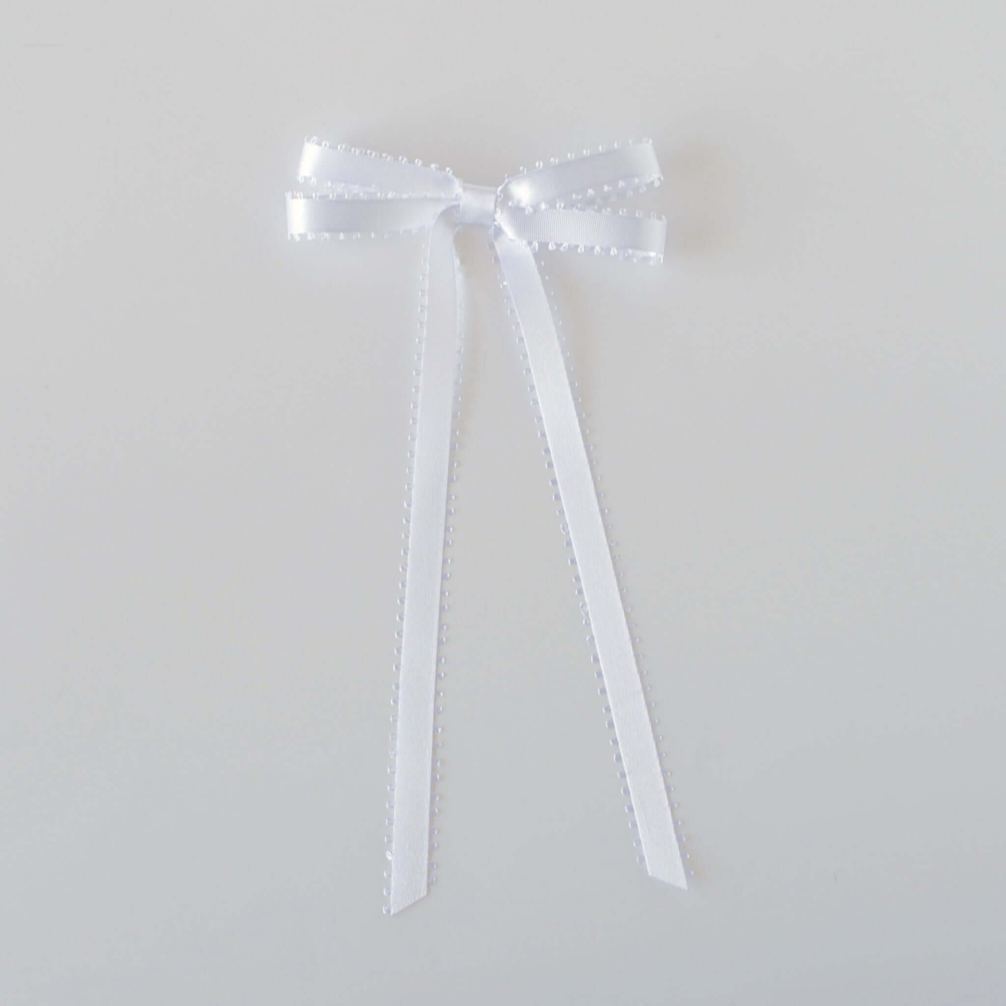 Olivia Picot Satin Bow accessory with picot edges, perfect for hairstyles of women and girls, available with a clip or barrette.