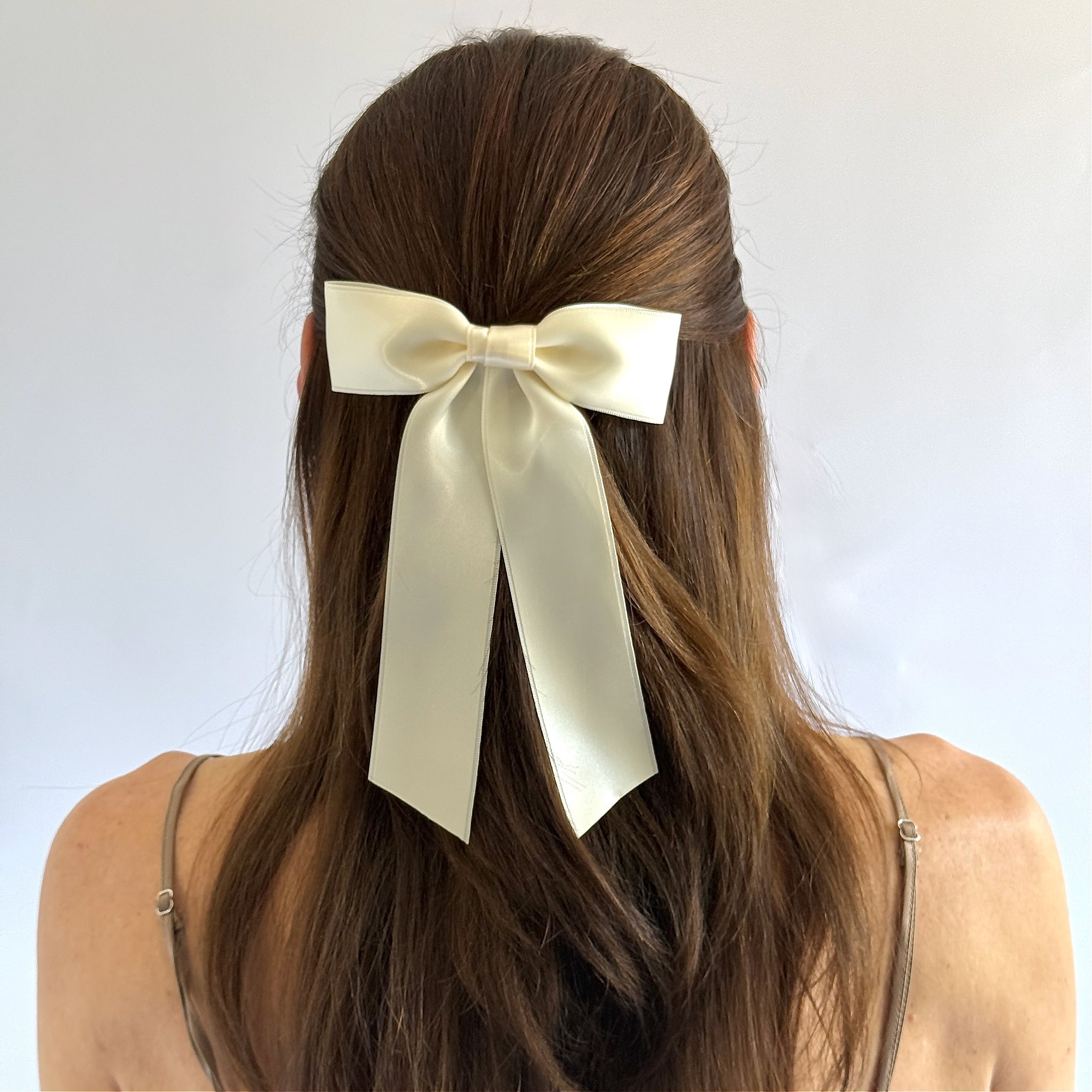 Zoe petite satin hair bow in ivory on model wearing a half up style.